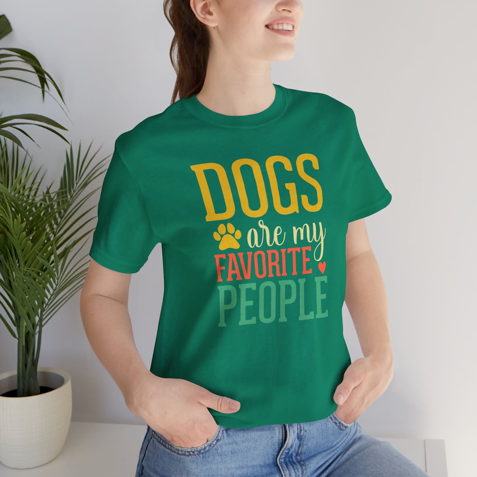 Person wearing a green t-shirt with 'DOGS are my FAVORITE PEOPLE' text, standing indoors.