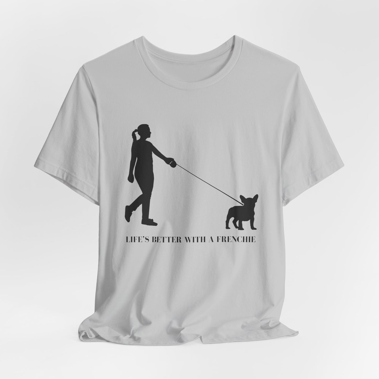 White t-shirt with black silhouette design of a person walking a dog and text 'Life's better with a Frenchie' on a white background.