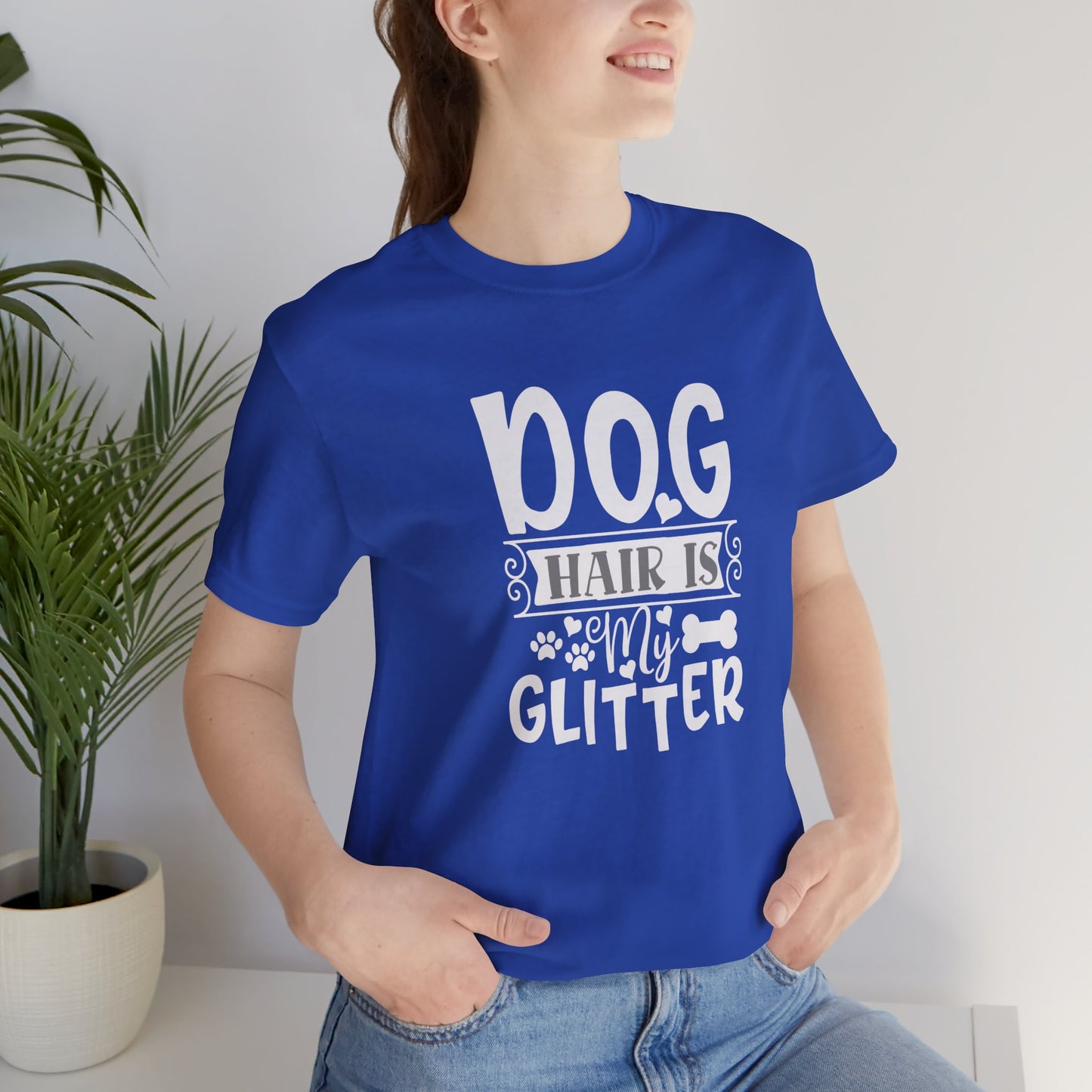 Person wearing a blue t-shirt with 'Dog hair is my glitter' text, standing indoors.