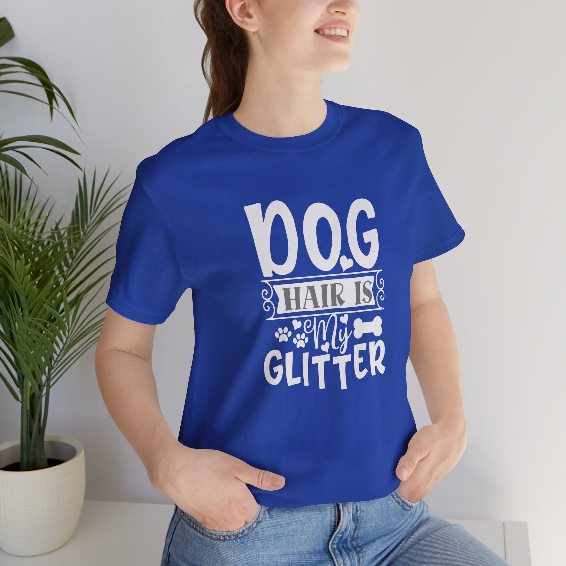 Person wearing a blue t-shirt with 'Dog hair is my glitter' text, standing indoors.