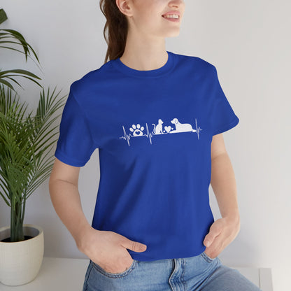 Person wearing a blue t-shirt with text, standing indoors next to a plant.