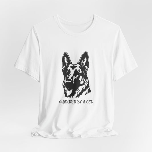 White t-shirt with a black dog graphic and text 'Guarded by a GSD' on a white background