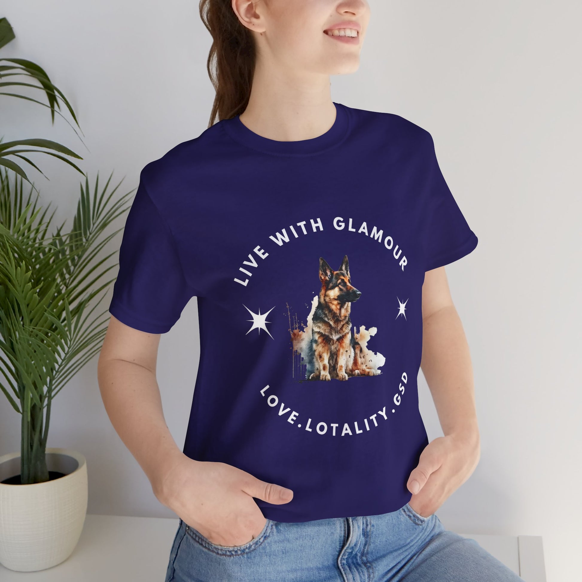 Person wearing a purple t-shirt with a dog graphic and text, standing indoors next to a plant.