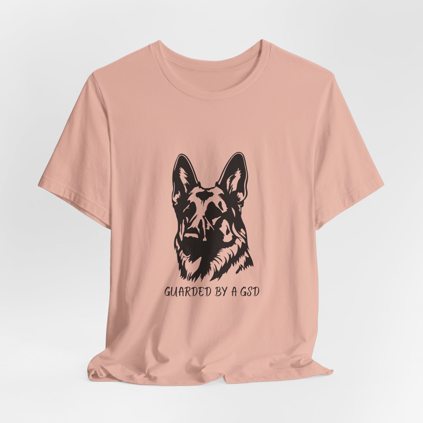 Pink t-shirt with a black dog graphic and text on a light gray background