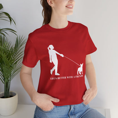 Person wearing a red t-shirt with a graphic and text, standing indoors next to a plant.