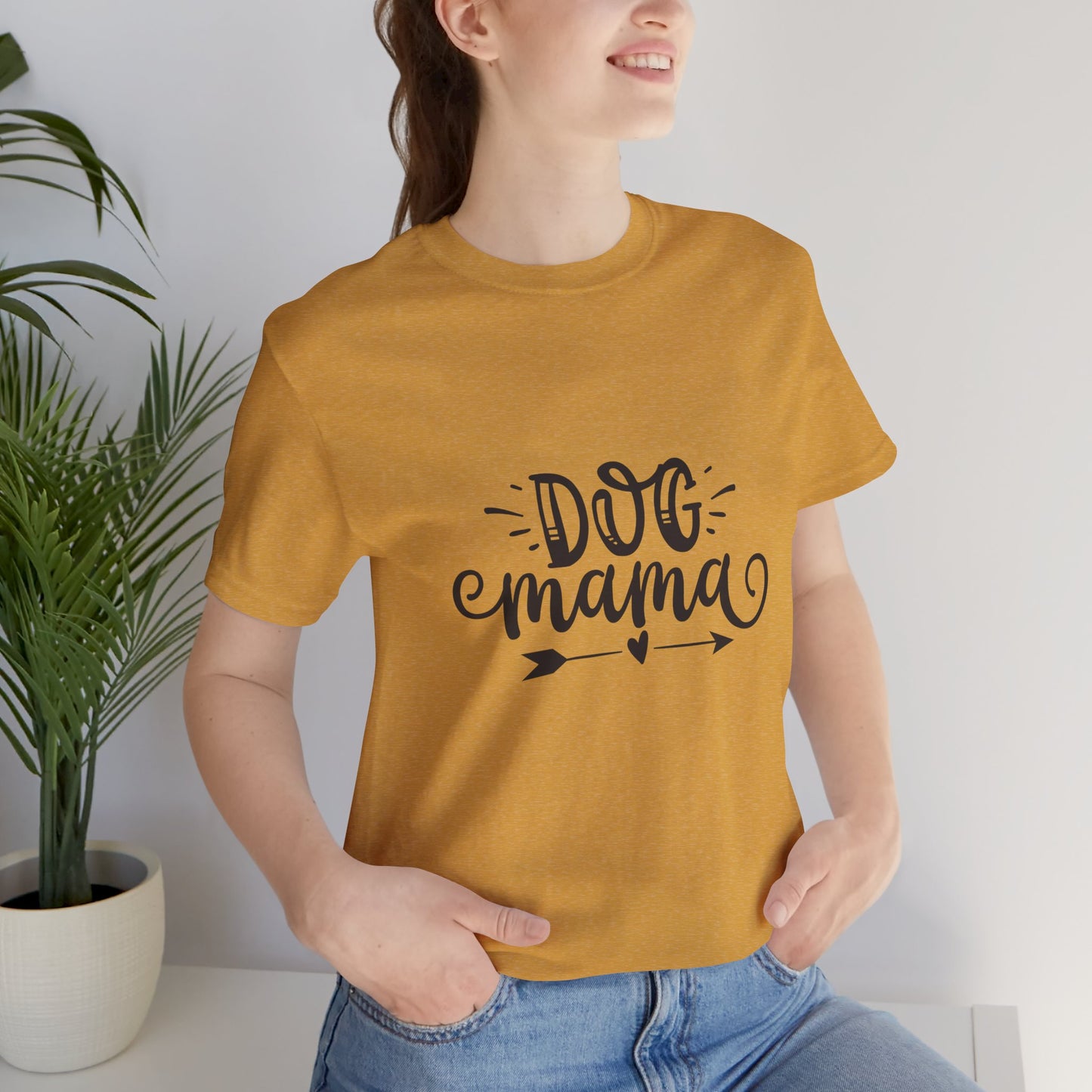 Person wearing a mustard yellow t-shirt with 'DOG mama' text, standing indoors.