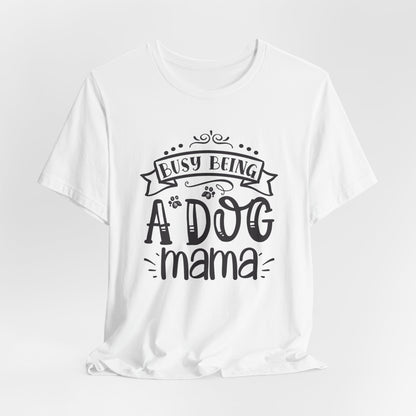 White t-shirt with 'Busy Being A Dog Mama' text on a light gray background